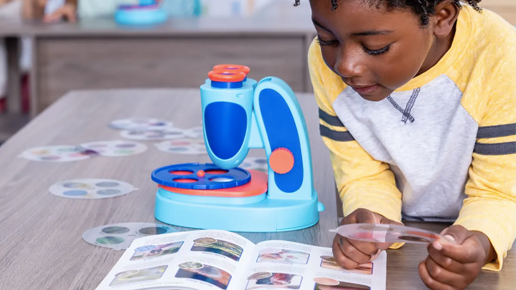 Young boy playing with toy slide microscope